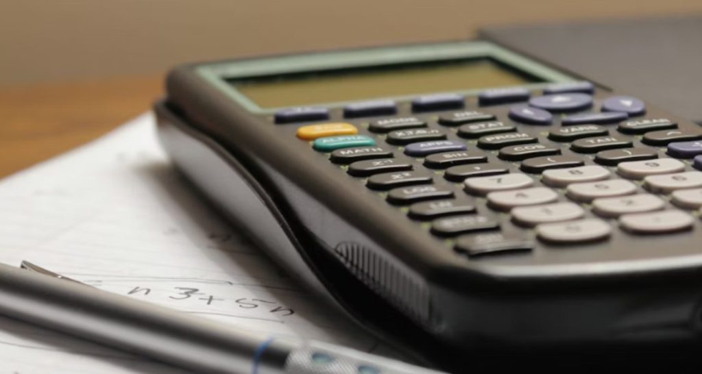 close-up focado em uma calculadora científica e materiais de estudo ou trabalho.