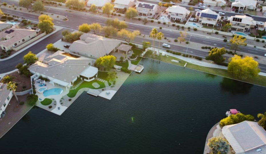 A imagem mostra uma vista aérea (drone) de um bairro residencial de alto padrão localizado às margens de um lago artificial.