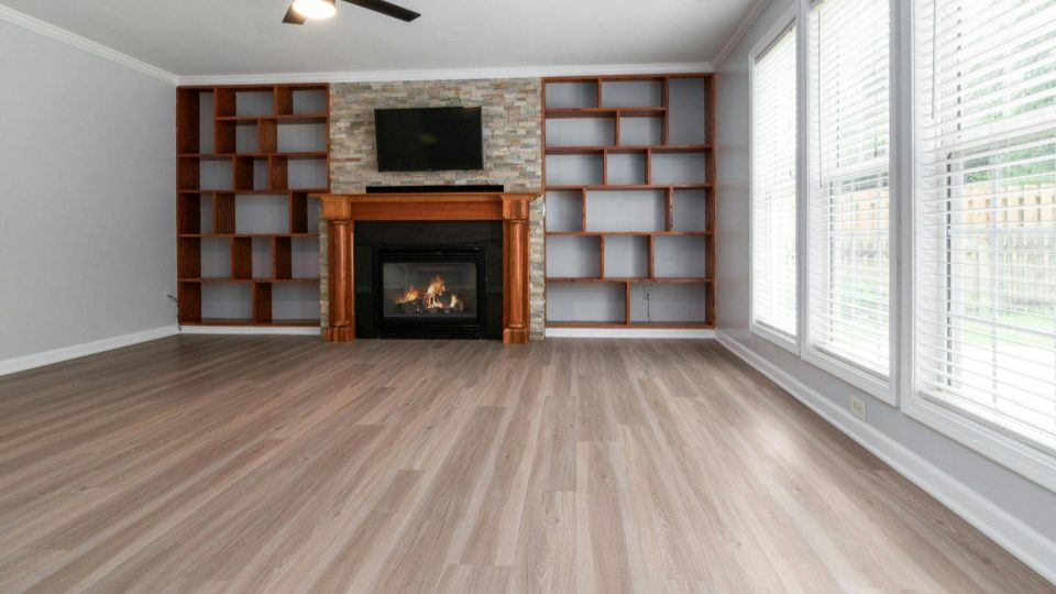 Esta imagem apresenta uma sala de estar ampla e moderna, destacando elementos arquitetônicos de madeira e uma lareira central.