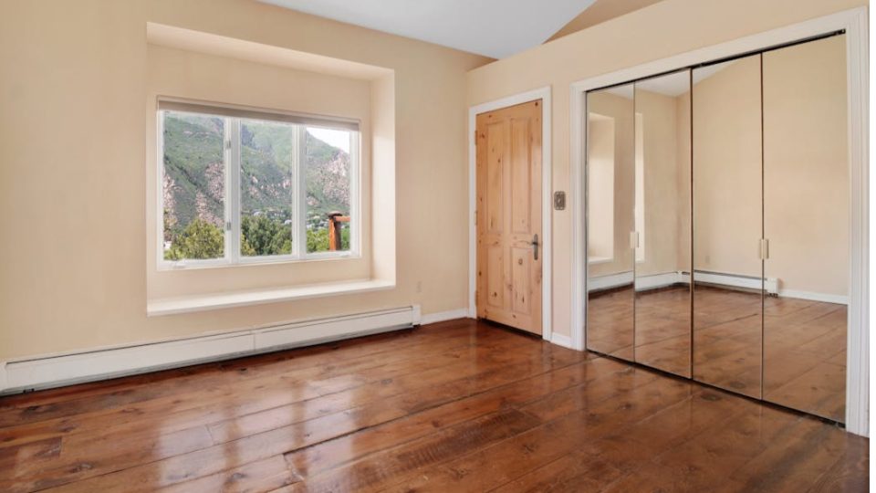 Esta imagem apresenta o interior de um quarto vazio, destacando-se pela vista natural e elementos de madeira.