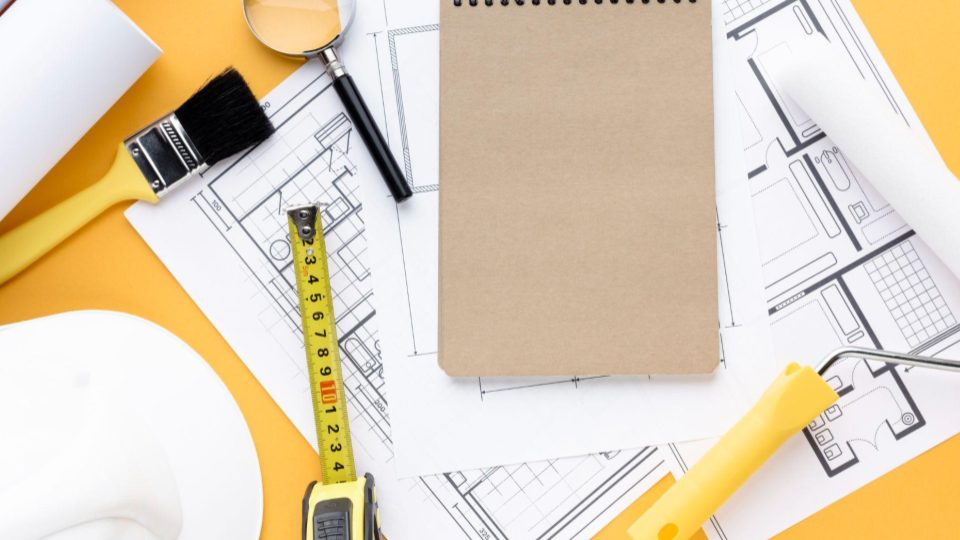 Esta imagem apresenta uma visão aérea organizada de ferramentas de construção e materiais de planejamento sobre um fundo amarelo vibrante.