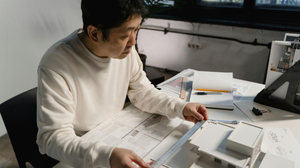 Um homem de meia-idade, com traços asiáticos, trabalha concentrado em sua mesa de escritório.