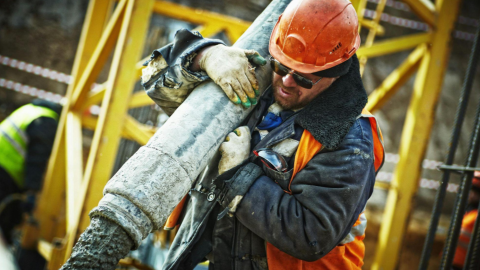 Esta imagem retrata a realidade bruta e o esforço físico do trabalho em um canteiro de obras.