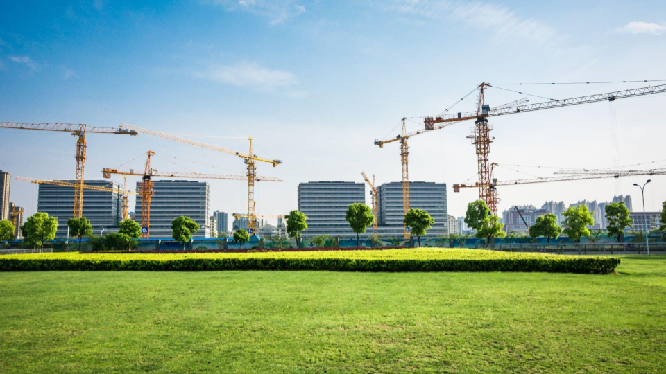 Esta imagem apresenta um cenário de desenvolvimento urbano em grande escala, destacando o contraste entre a natureza preservada e a construção civil ativa.