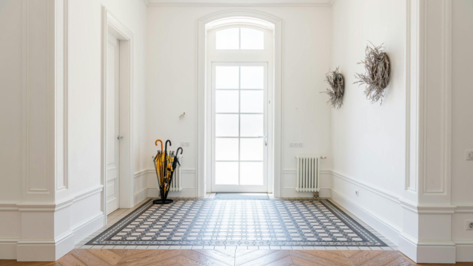 Paredes brancas com detalhes em boiserie (molduras) e rodapés altos e trabalhados, que dão um ar elegante e imponente ao espaço.