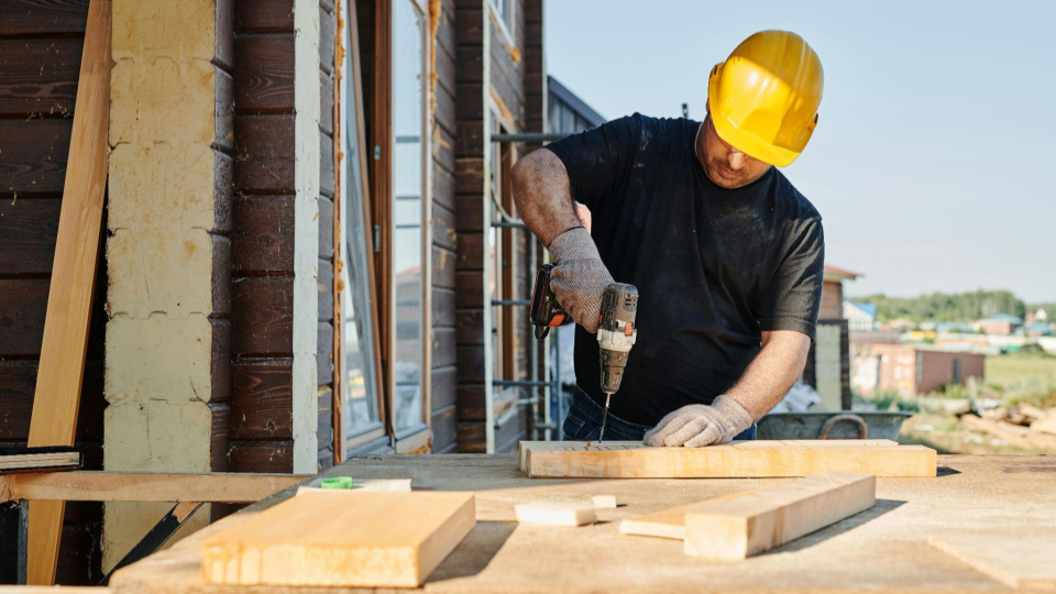 imagem foca no trabalho manual e técnico de um operário em um canteiro de obras.