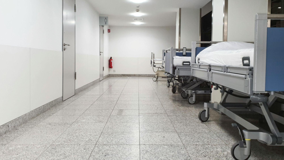 Uma zona de transição com várias macas alinhadas. O revestimento das paredes e o rodapé precisam suportar o contato físico frequente sem descascar ou criar frestas que acumulem sujeira.