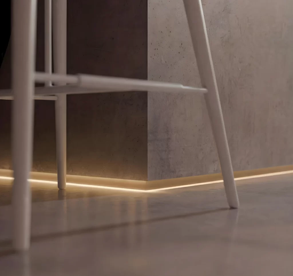 Detalhe de uma estrutura metálica branca passando por um painel de concreto liso, em ambiente interno com luz quente no piso de cimento e perspectiva em close.