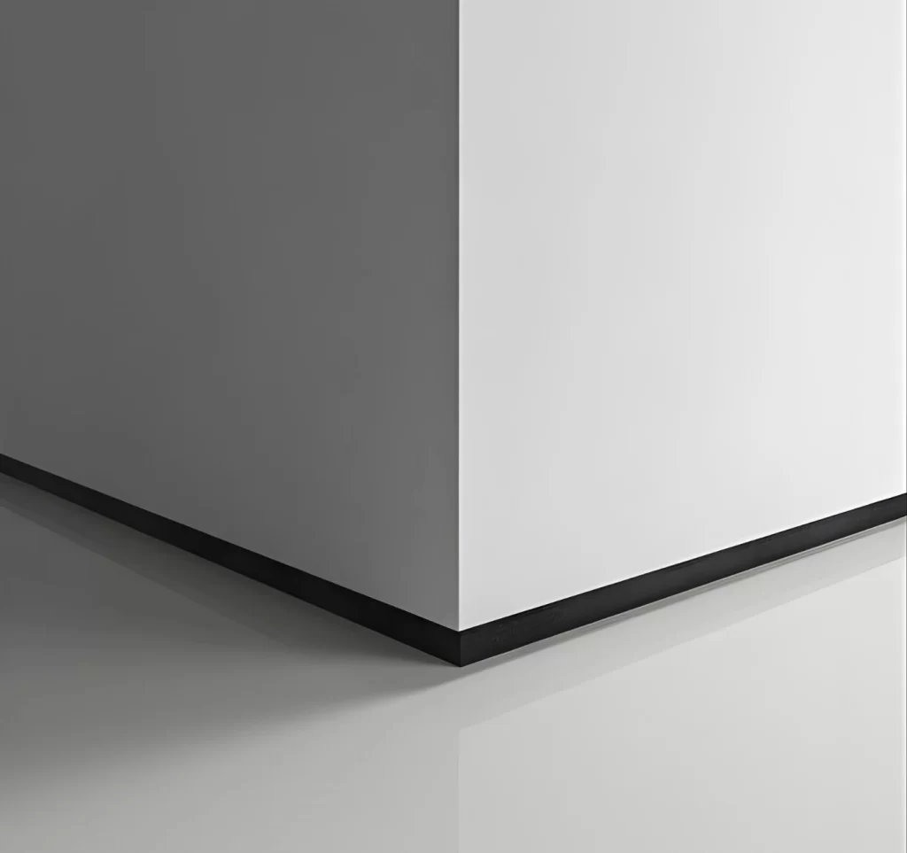 Detalhe de um rodapé com acabamento em cinza escuro e branco, formando um contraste com base preta e reflexão suave no piso, em composição minimalista e moderna.