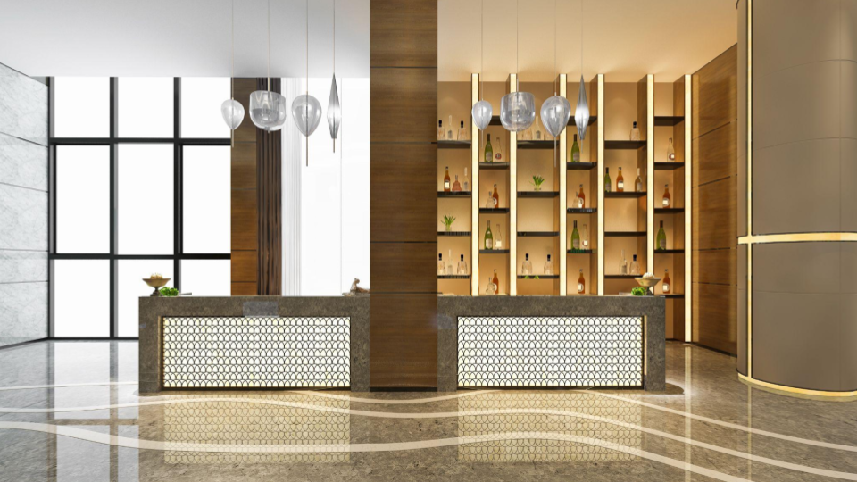 Recepção de hotel luxuosa com balcões iluminados, piso espelhado e bar ao fundo.