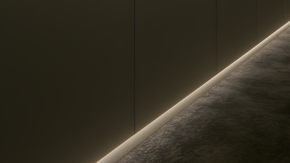 Foto conceitual focada em um corredor ou parede escura. Na junção entre o painel vertical e o piso de textura rústica escura, destaca-se um feixe de luz indireta contínuo e acolhedor (fita de LED embutida em rodapé invertido ou perfil de LED).
