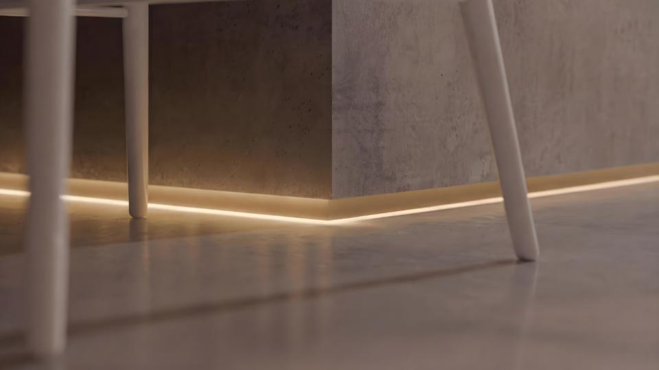 Detalhe de rodapé com fita LED embutida iluminando a junção da parede de concreto com o piso.